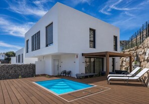 A modern two-story house with a swimming pool, outdoor seating, and a stone wall. - House in Mijas • SeaViews • Pool • PrivateTerrace. (AN)