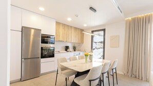 Een moderne keuken met een ingebouwde oven, een koelkast en een eethoek met een tafel en stoelen.