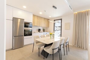 Eine moderne Küche mit Einbauofen, Kühlschrank und Essbereich mit Tisch und Stühlen.