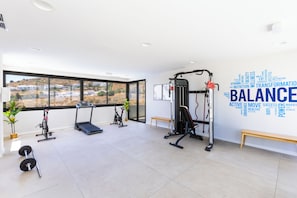 A modern gym with exercise equipment, large windows, and a motivational word cloud on the wall. - House in Mijas • SeaViews • Pool • PrivateTerrace. (AN)