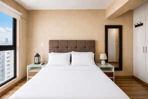 A hotel room with a large bed, a nightstand with a lamp, a mirror, and a view of the city through a window. - Depa moderno Miraflores Gym parking 811 (Lima)