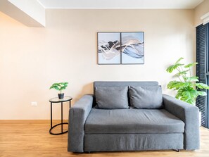 A modern living room with a grey sofa, a small round table with a plant, and abstract wall art. - Depa moderno Miraflores Gym parking 811 (Lima)