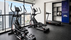Ein Fitnessraum mit zwei Crosstrainern, einem Laufband und einer Wand mit einem Motivationsposter.
