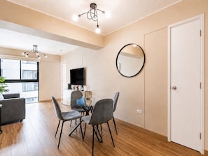 A modern living room with a glass dining table, grey chairs, a flat-screen TV, and a round mirror on the wall. - Depa moderno Miraflores Gym parking 811 (Lima)