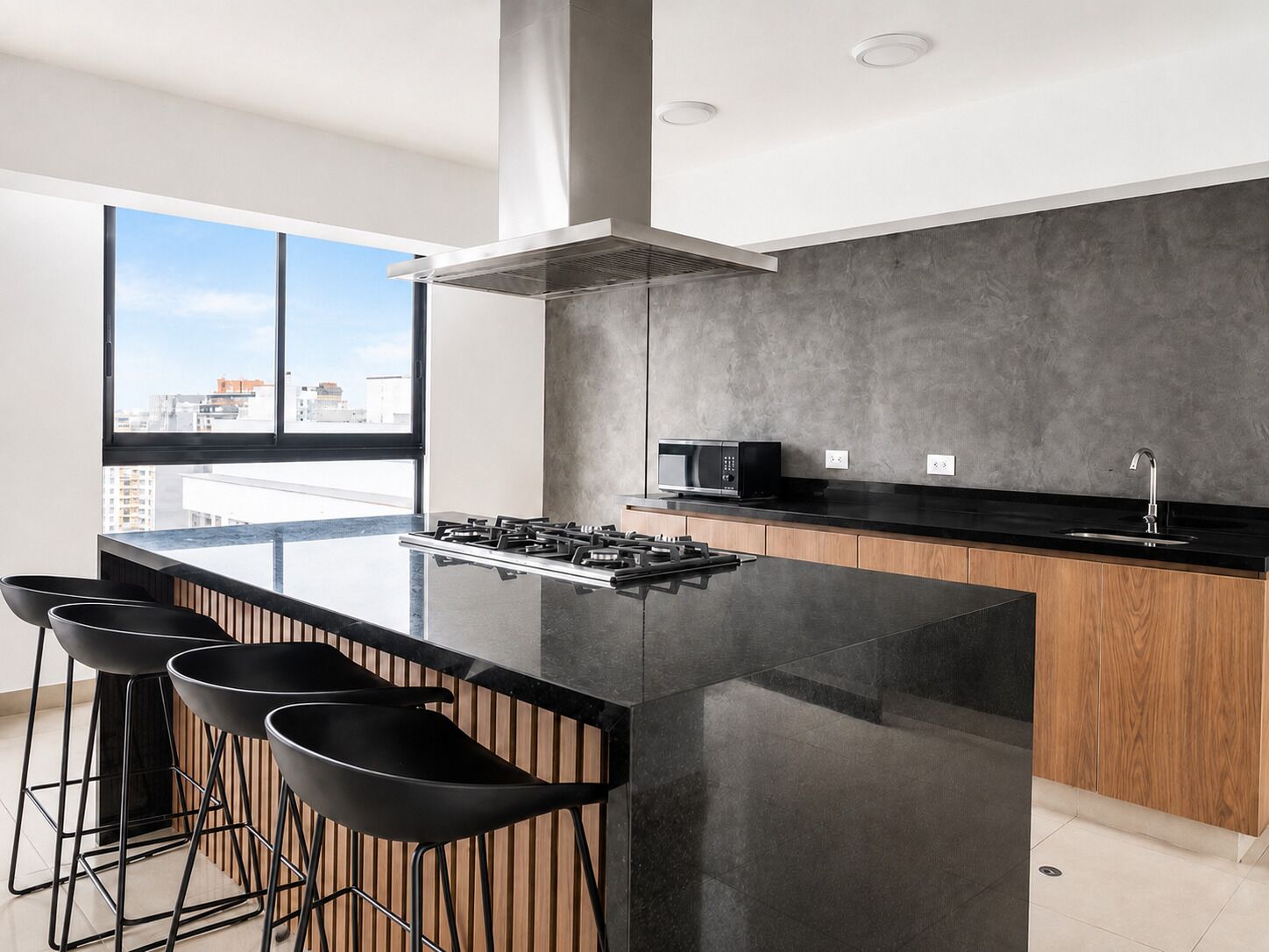 A modern kitchen with a large island, bar stools, a microwave, and a view of the city.