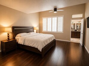 Quarto com cama, mesas de cabeceira, ventoinha no teto e janela com persianas.