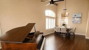 A spacious room with a grand piano, a dining area, and a large window. - Upscale Desert Oasis - Heated Pool - Golf (Scottsdale)