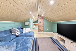 Ein gemütliches Schlafzimmer im Dachgeschoss mit einem großen Bett, einem Fernseher und einer Ziegelwand.