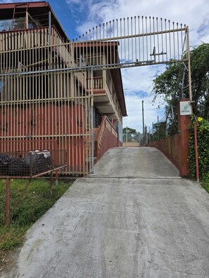A gated entrance to a building with a concrete pathway leading to a gated driveway.