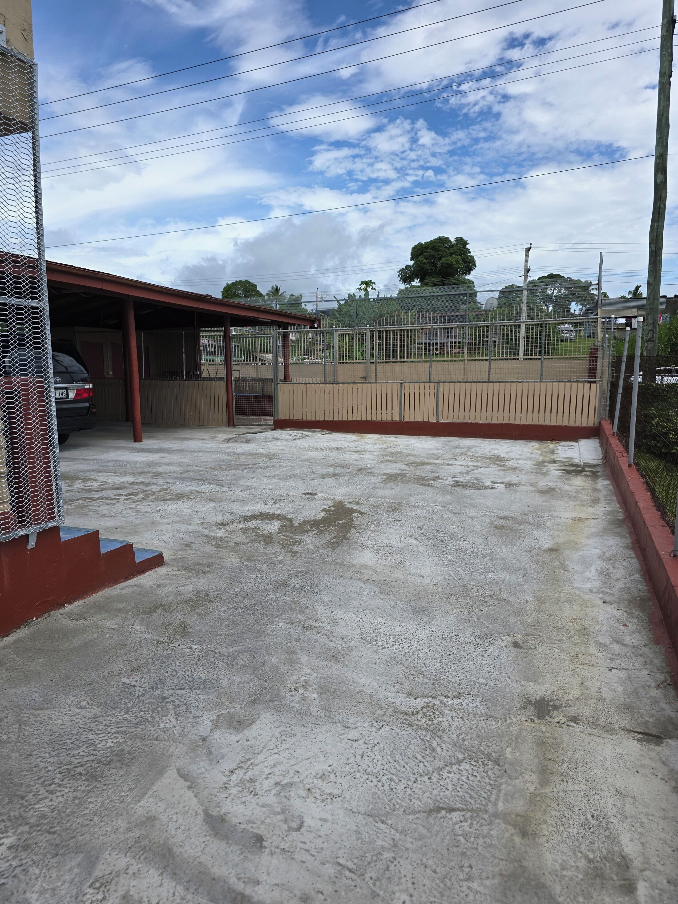 Uma área de estacionamento com uma lavagem de carros coberta, uma área cercada e piso de concreto.