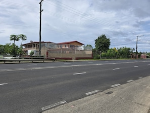 Una carretera con un edificio a la izquierda, una valla y árboles.