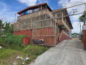 A multi-story building with a gated entrance, a staircase, and a balcony with clothes hanging.