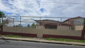 Zona residencial con entrada vigilada y una calle pavimentada al frente.