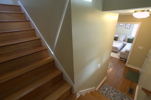 A wooden staircase leading to a living area with a couch and a rug. - First Street Fanatics (Bloomington)