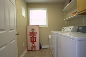 A laundry room with a door, a window, a washing machine, and a drying machine. - First Street Fanatics (Bloomington)