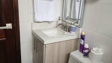 A bathroom with a toilet, sink, mirror, and towel rack.