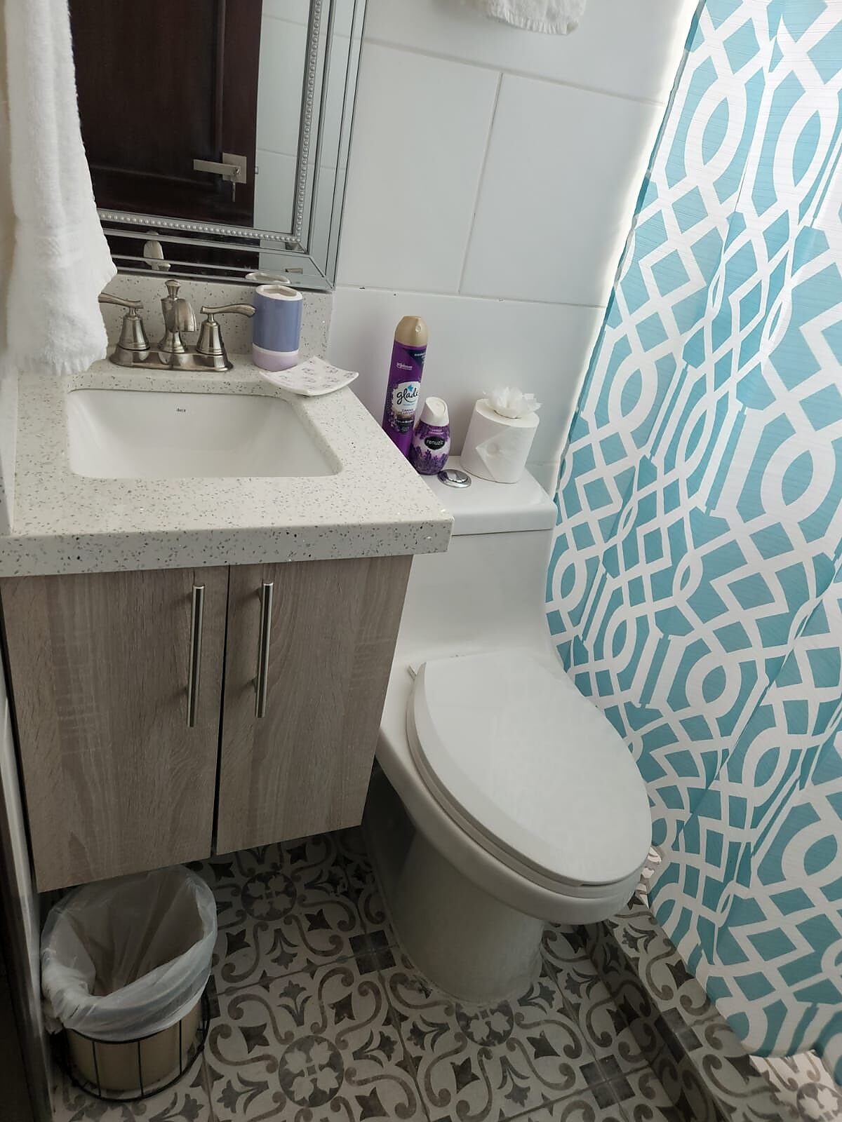 Un baño con lavamanos, inodoro y baldosas de piso con diseño.