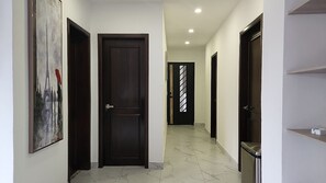 A hallway with dark wooden doors, a marble floor, and a painting on the wall.