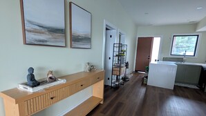 Ein modernes Interieur mit einem Holzkonsolentisch, zwei abstrakten Gemälden und einem Flur, der in einen Küchenbereich führt.