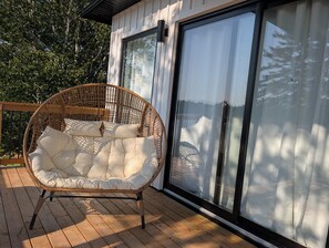 Ein Korbstuhl mit Kissen auf einer Terrassenfläche.