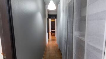 A hallway with a tiled floor, a hanging light fixture, and a door at the end.