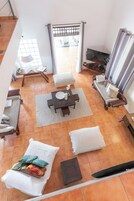 Un amplio salón con techo alto, una mesa de comedor, sofás y un televisor.