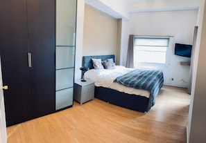 A bedroom with a bed, nightstand, wardrobe, and a TV. - Chelsea 1-Bed Flat 12 on King's Road | Sleeps 3 (Greater London)