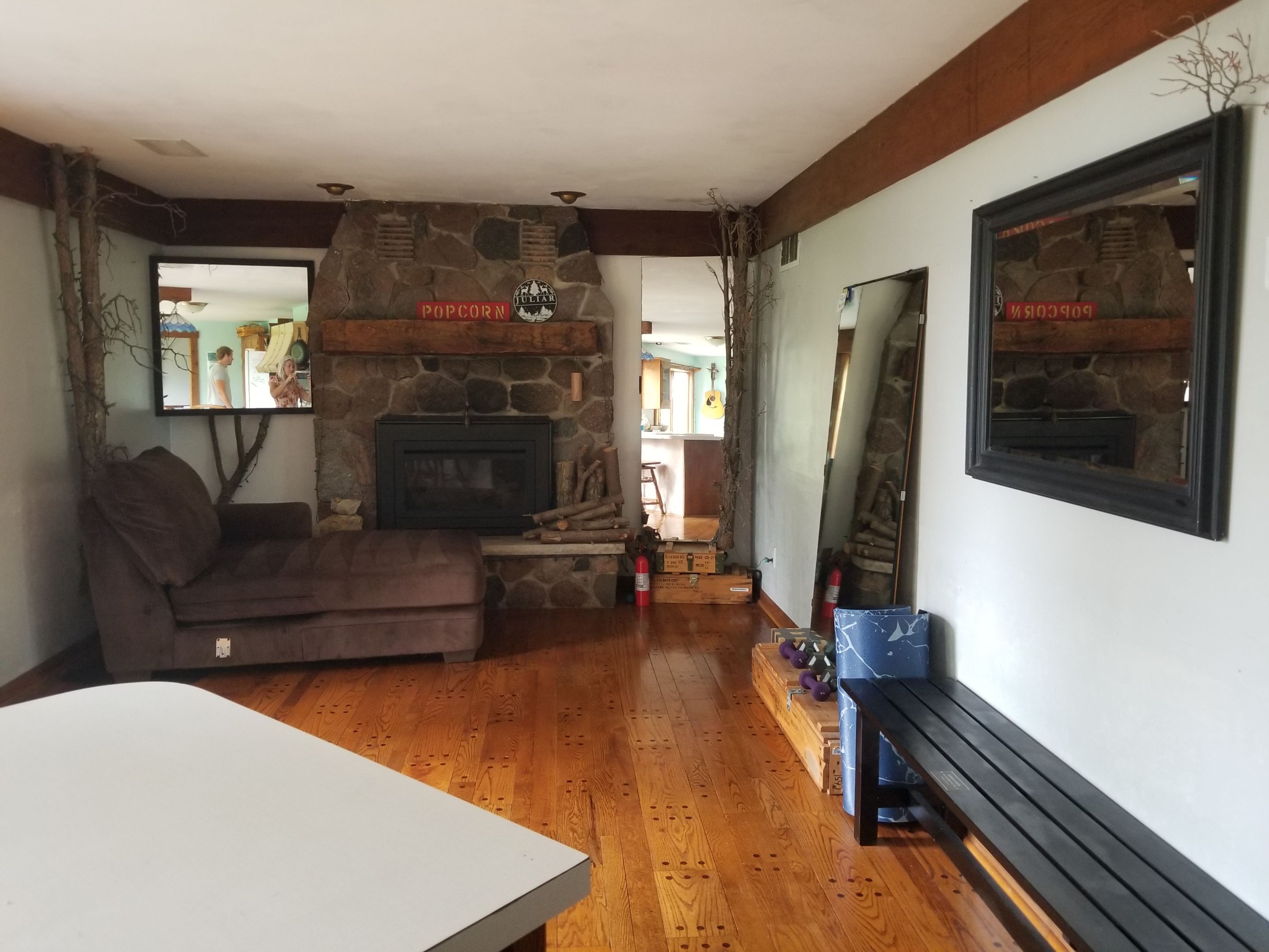 A living room with a stone fireplace, a sofa, a wooden table, and a bench.