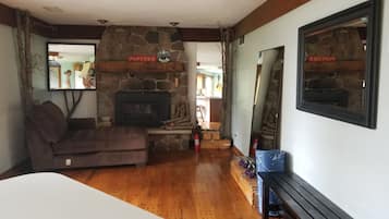 A living room with a stone fireplace, a sofa, a wooden table, and a bench.