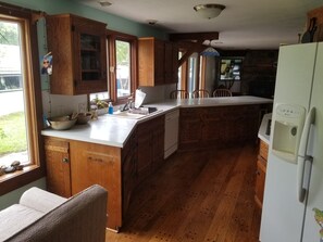 A kitchen with wooden cabinets, a white countertop, a sink, and a built-in dishwasher.