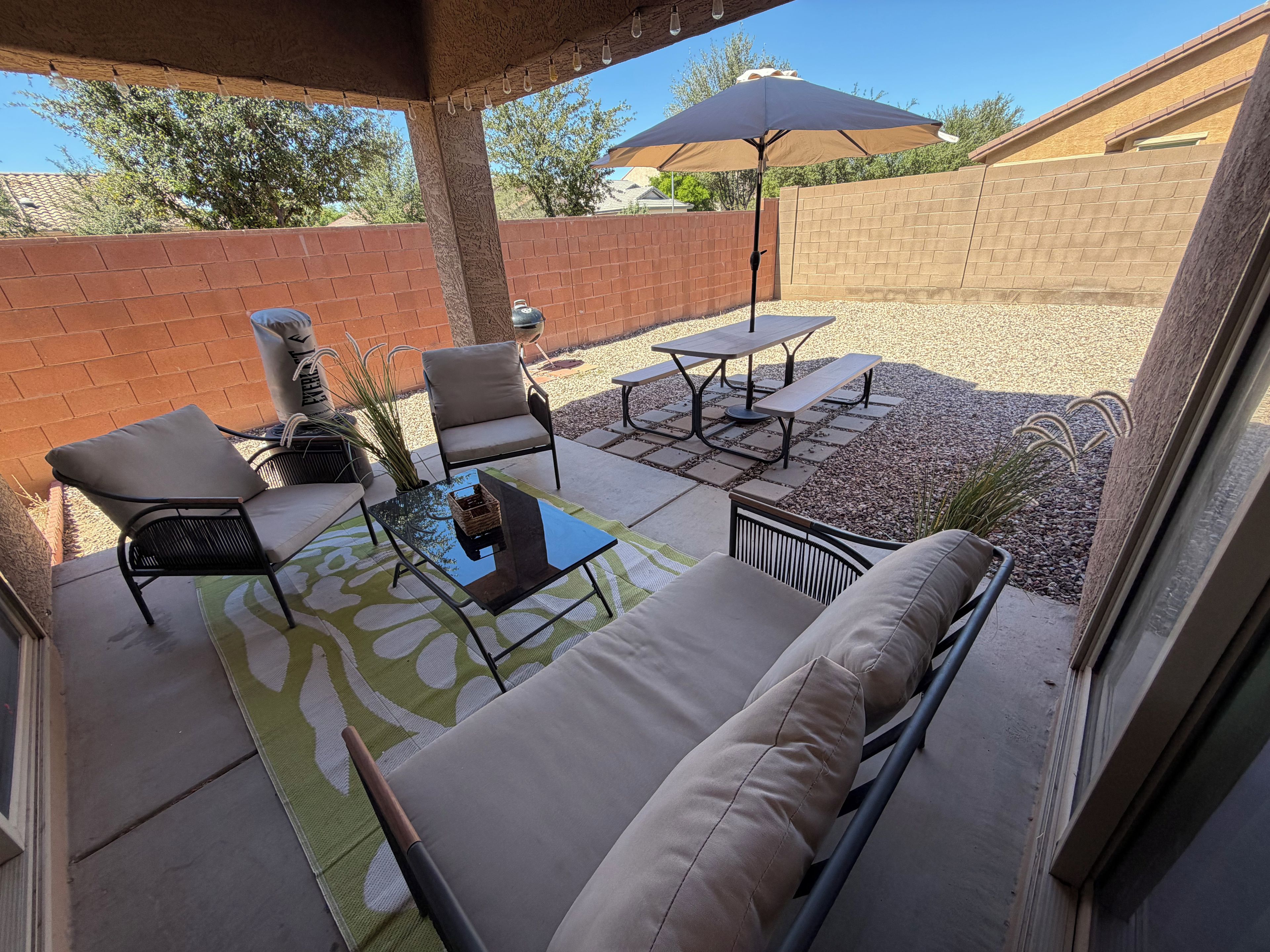 An outdoor patio with a sofa, chairs, a table, and a barbecue grill.