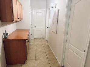 Un pasillo estrecho con un mostrador de madera, una puerta blanca y una lámpara fijada a la pared.