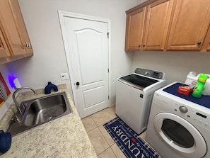 A laundry area with a washing machine, dryer, and a sink.
