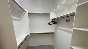 A walk-in closet with open shelving, a hanging rod, and a carpeted floor.