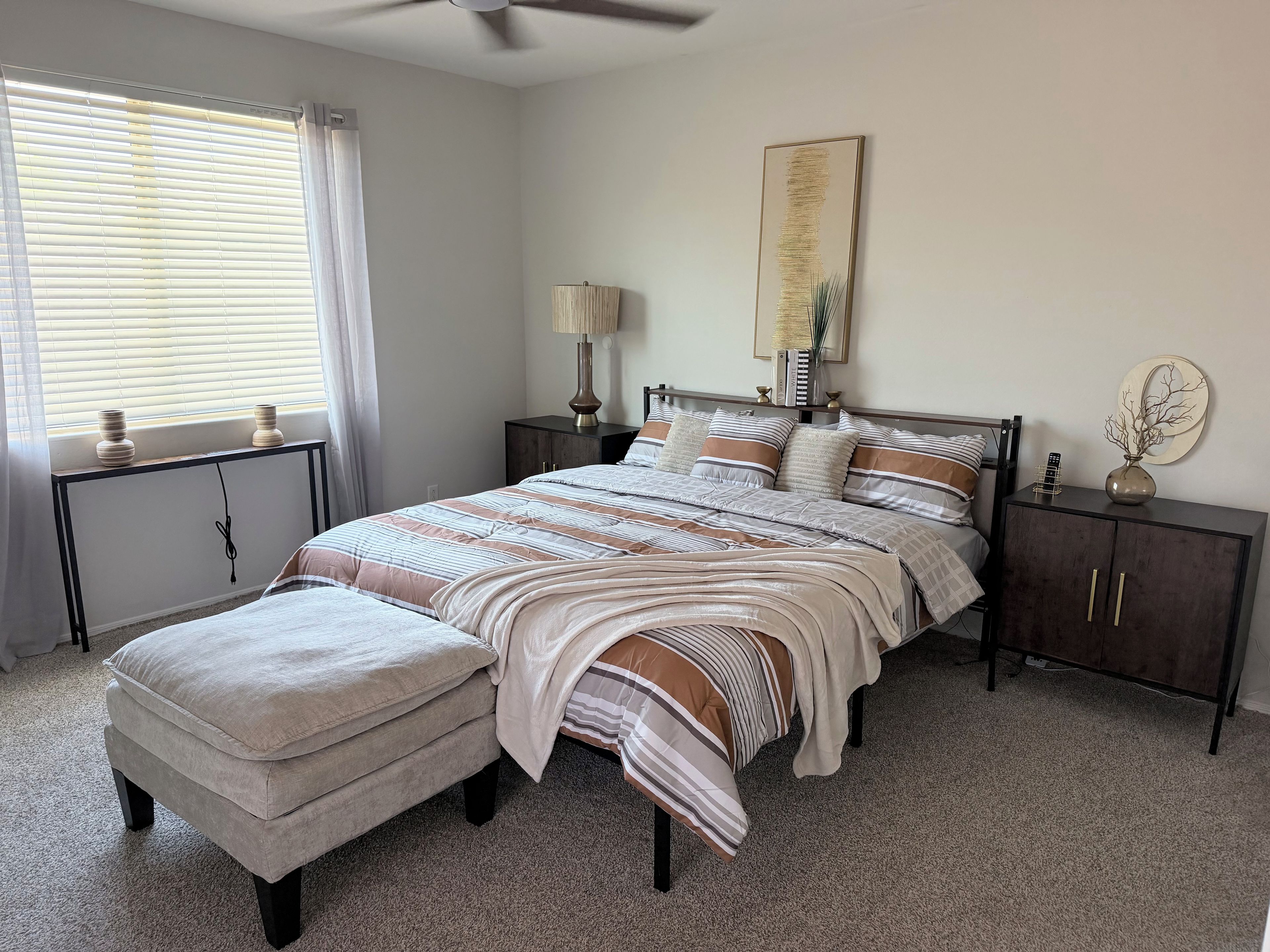 A bedroom with a bed, nightstands, a lamp, a vase, and a ceiling fan.