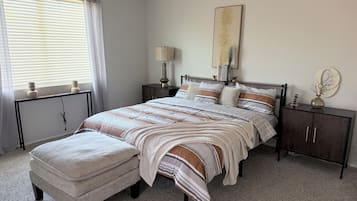 A bedroom with a bed, nightstands, a lamp, a vase, and a ceiling fan.