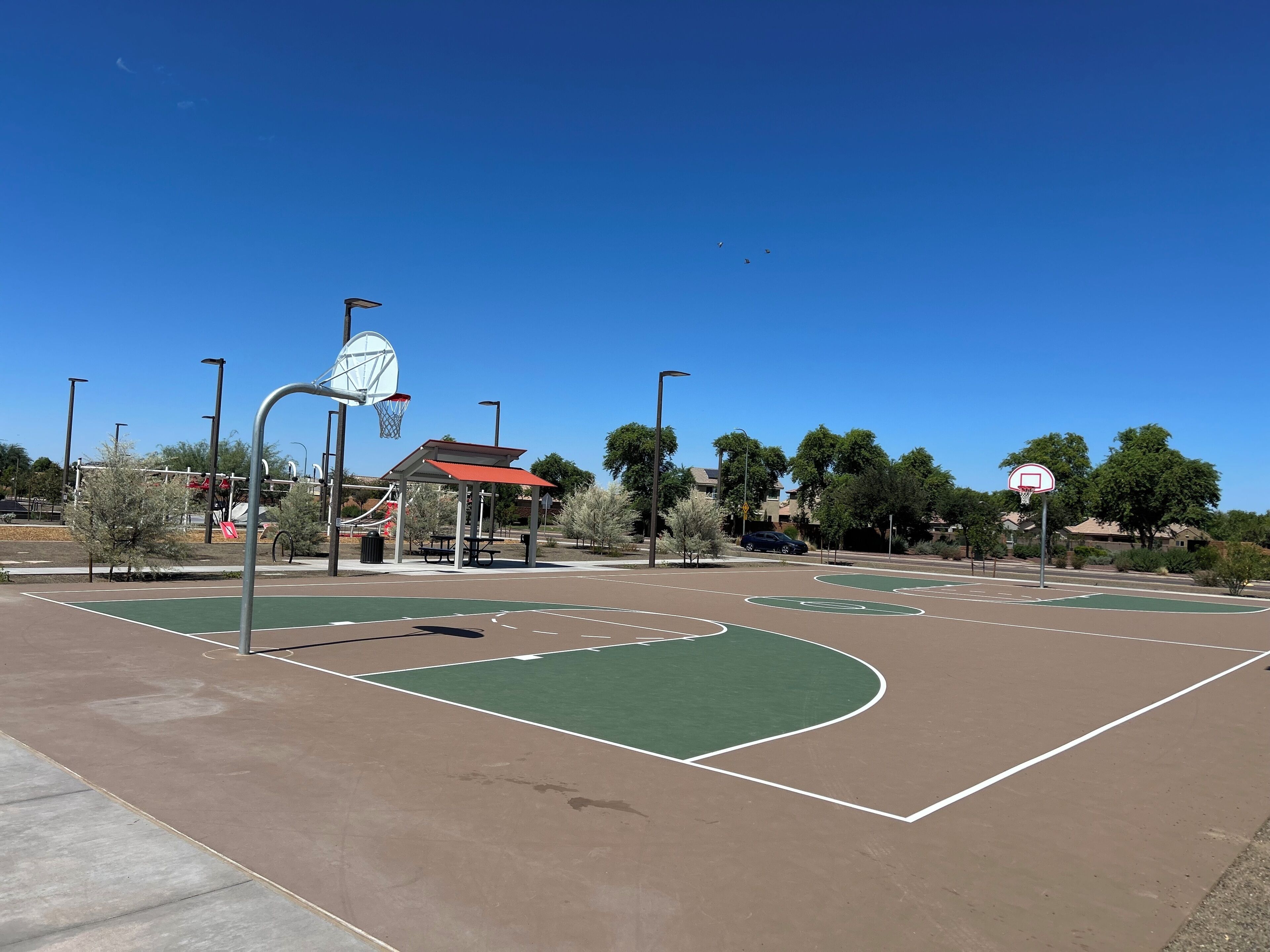 An outdoor basketball court with a pavilion, picnic tables, and a satellite dish.