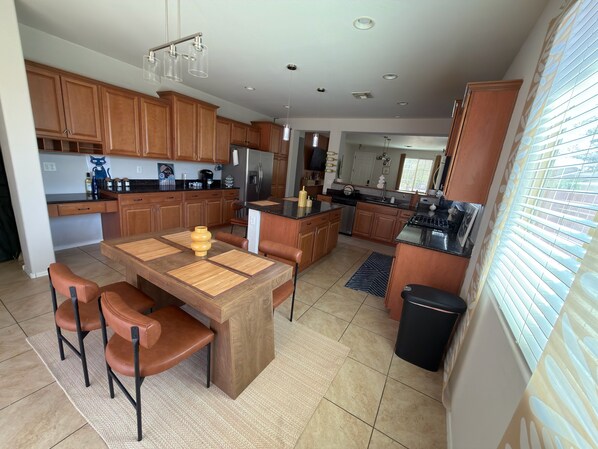 A modern kitchen with wooden cabinets, a dining table with chairs, and a built-in oven.