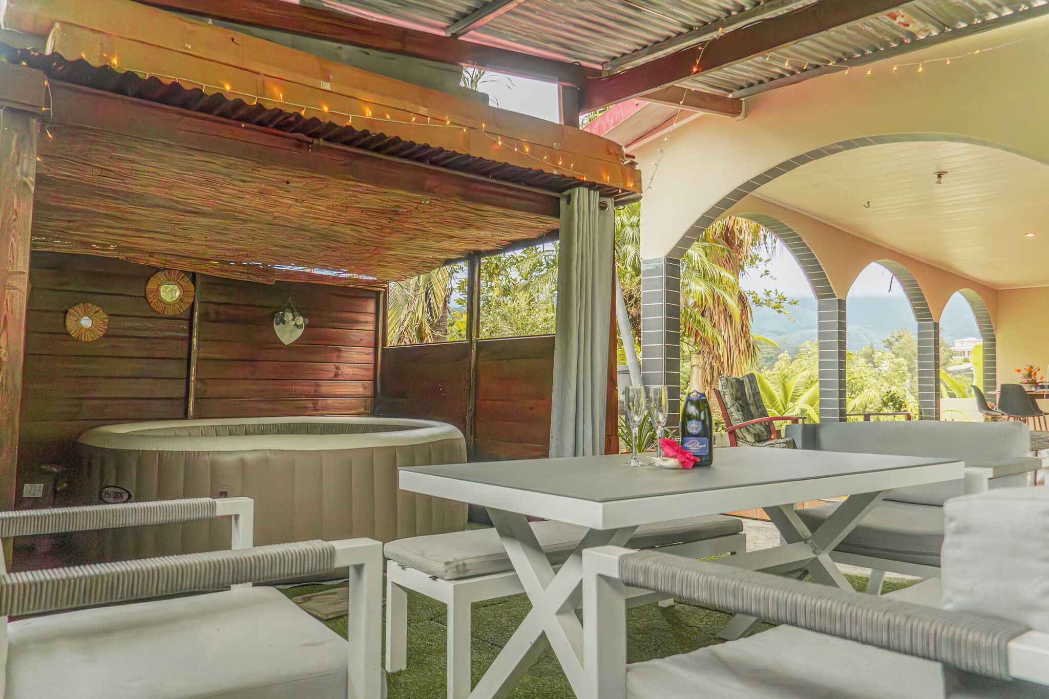 An outdoor patio area with a table, chairs, a hot tub, and a view of the landscape.