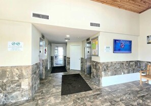 A hotel lobby with a marble floor, a 'No Smoking' sign, and a 'No Smoking Allowed in Common Walkways, Stairwells or Condo Balconies' sign. - Gulf Front View + Beach Service + Pool + King Bed (Gulf Shores)