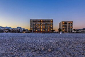 A beachfront hotel with multiple floors, balconies, and a well-lit facade. - Gulf Front View + Beach Service + Pool + King Bed (Gulf Shores)