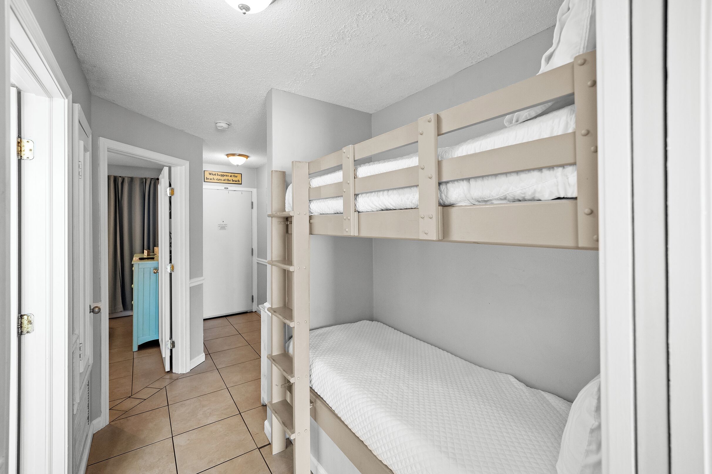 A bunk bed room with a door leading to a bathroom and a hallway.