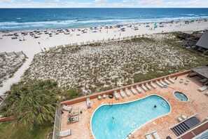 A beach resort with a swimming pool, beach chairs, and umbrellas. - Gulf Front View + Beach Service + Pool + King Bed (Gulf Shores)