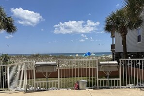 A gated beachfront property with a view of the ocean, a beach umbrella, and a trash can. - Gulf Front View + Beach Service + Pool + King Bed (Gulf Shores)