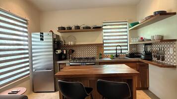 Une cuisine moderne dotée d’un îlot central, de tabourets de bar, d’un réfrigérateur et d’un ventilateur de plafond.