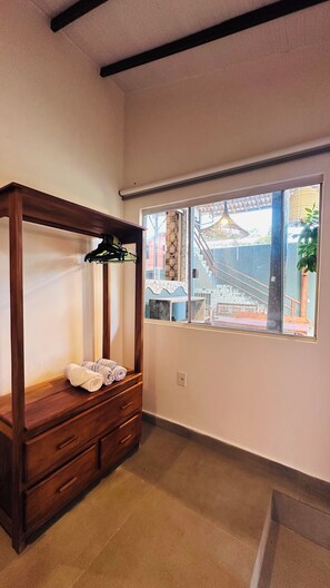 A room with a wooden wardrobe, a window with a view of a building outside, and a tiled floor. - Pousada Refugá (Porto Seguro)