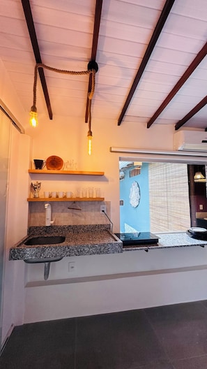 Una cocina con encimeras de granito, luminarias colgantes y vistas al exterior.