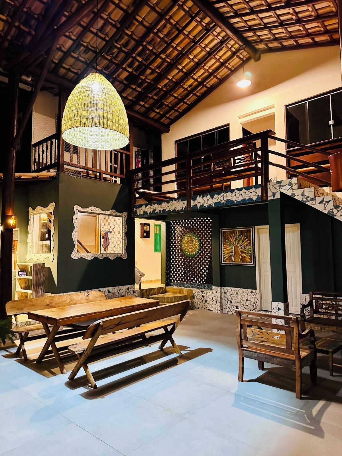 A spacious interior with a high ceiling, a wooden staircase, and a dining area with benches.
