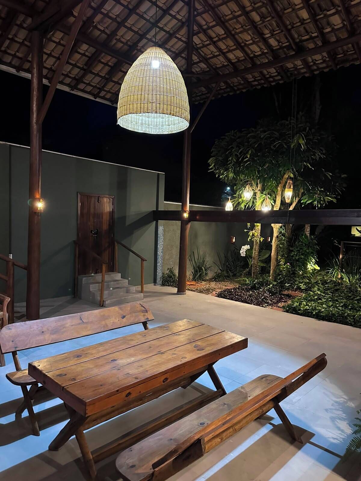 An outdoor patio with wooden benches and a hanging light fixture.