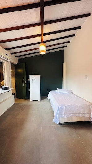Una habitación con cama, refrigerador, lavamanos y lámpara colgante.